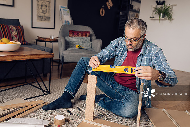 在他的客厅里制作家具的中年男人图片素材