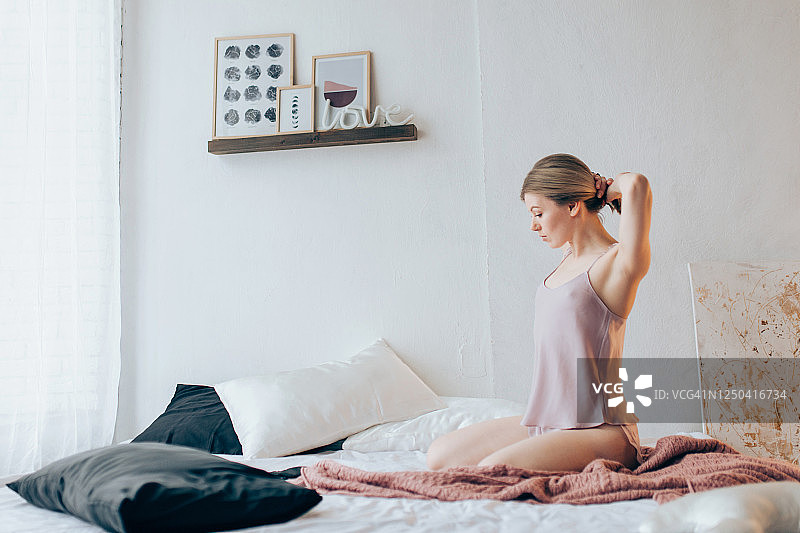 坐在床上扎头发的年轻女人图片素材