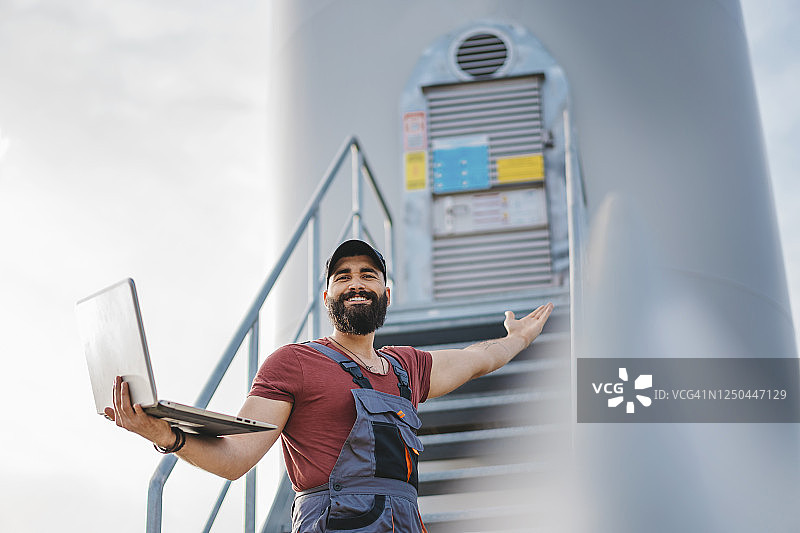 工厂工人在风力涡轮机上使用笔记本电脑控制机器图片素材