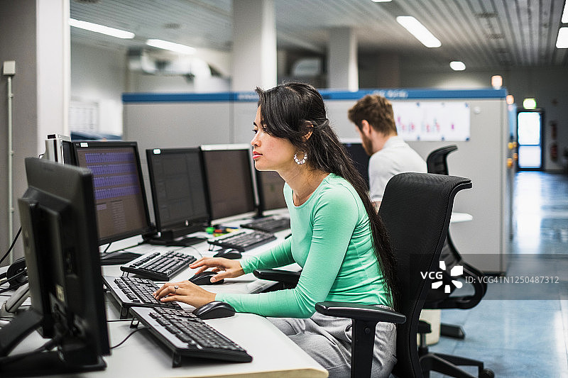 在印刷厂办公室的电脑桌前工作的女人图片素材