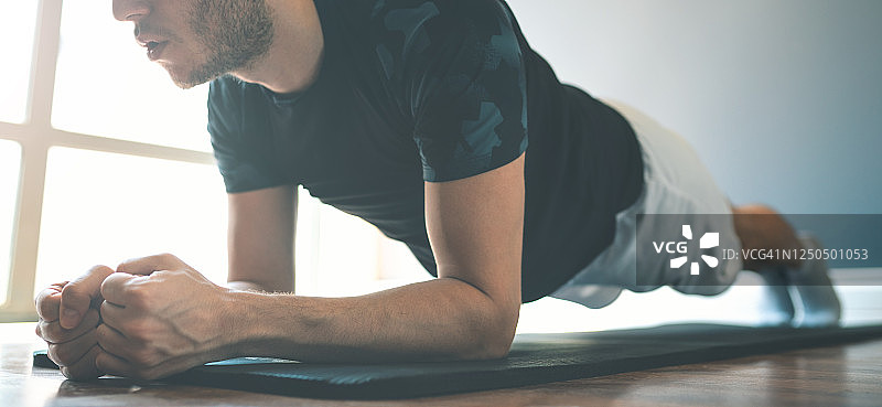 年轻的运动男子在健身垫上做平板支撑图片素材