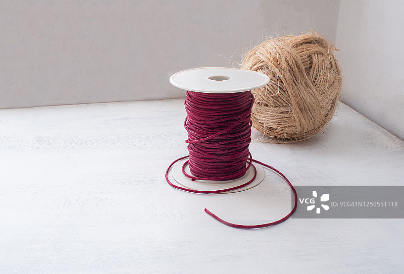 白色桌子和墙壁上的暗红色蜡线与粗麻线团图片素材