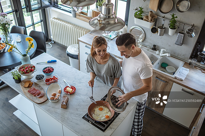 做早餐鸡蛋。厨房里的年轻夫妇图片素材