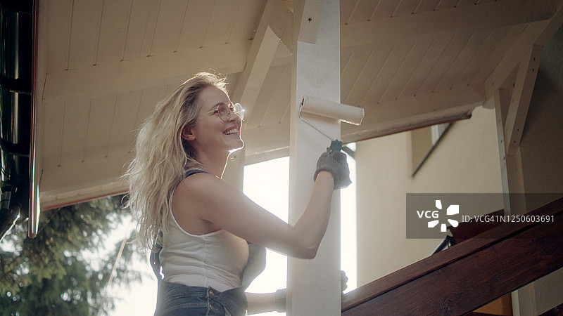 隔离期间的门廊翻新，女人粉刷柱子和墙壁图片素材