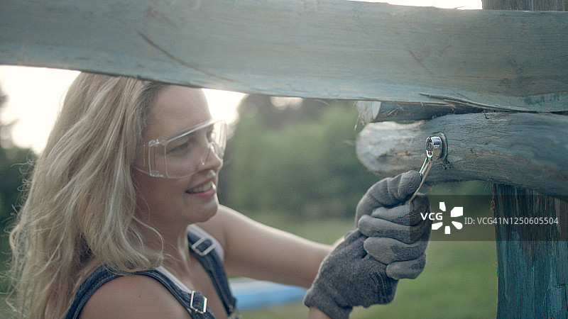 女人建造木制凉棚。使用扳手。花园DIY项目图片素材