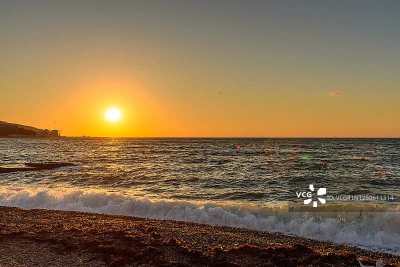 雅尔塔鹅卵石海滩的黎明，蓝色的海面和飞鸟为背景图片素材