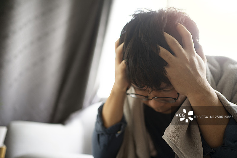 感觉不适头痛的亚洲青年男子在家中沙发上睡觉图片素材