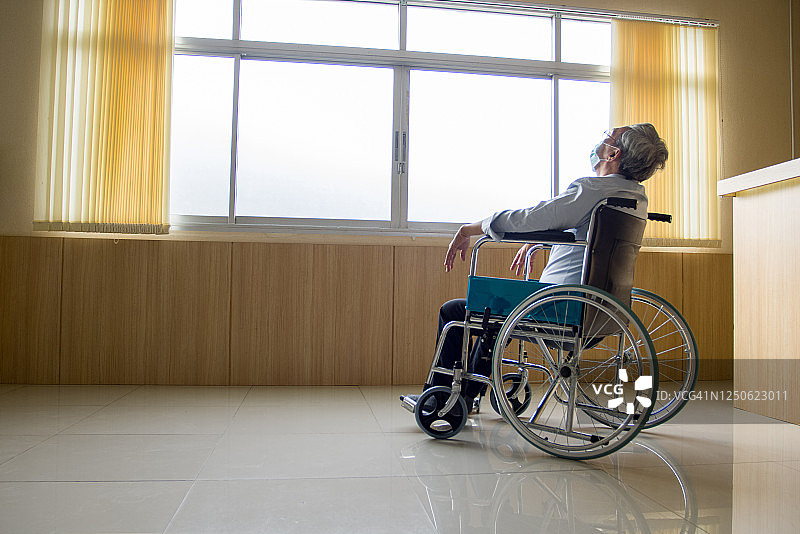 一位年长的亚裔人士坐在轮椅上图片素材