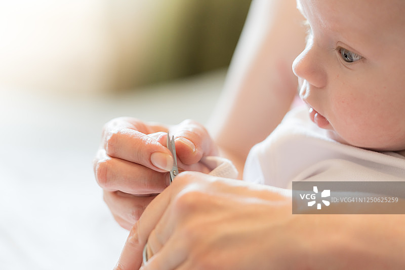 母亲用剪刀给婴儿剪指甲图片素材