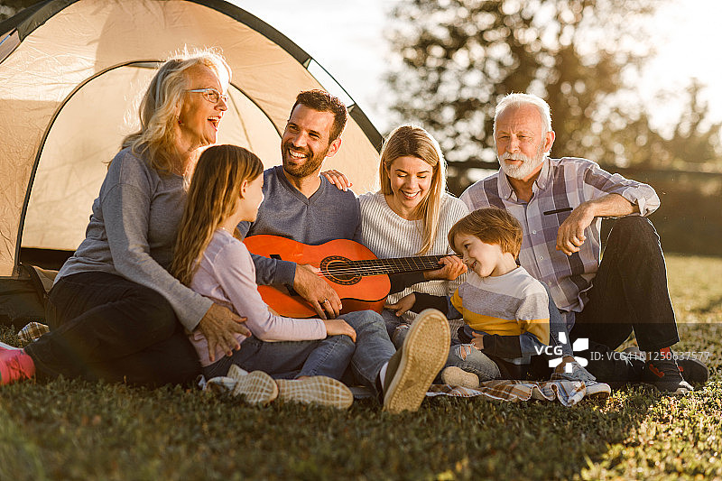快乐的大家庭在野外露营时享受吉他音乐图片素材