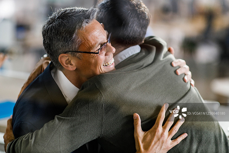 在办公室拥抱的快乐商业伙伴图片素材