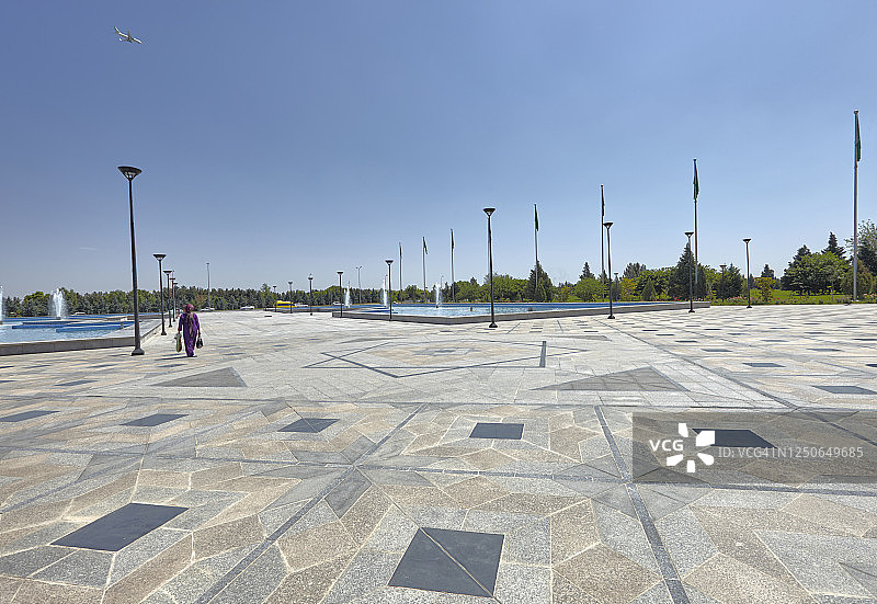 在土库曼斯坦阿什哈巴德的土库曼巴希清真寺前空地上行走的女图片素材