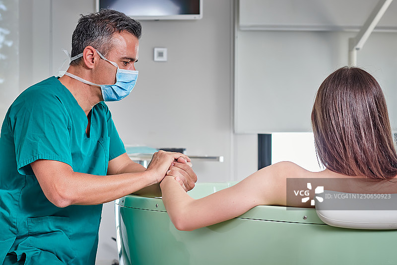 医生在水中分娩中握住孕妇的手图片素材