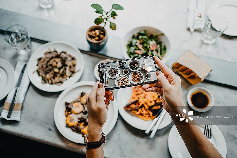 餐厅里用手机给食物拍照的女人图片素材