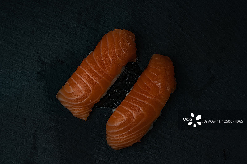 日式料理：深色木质背景上的三文鱼寿司和酱油图片素材