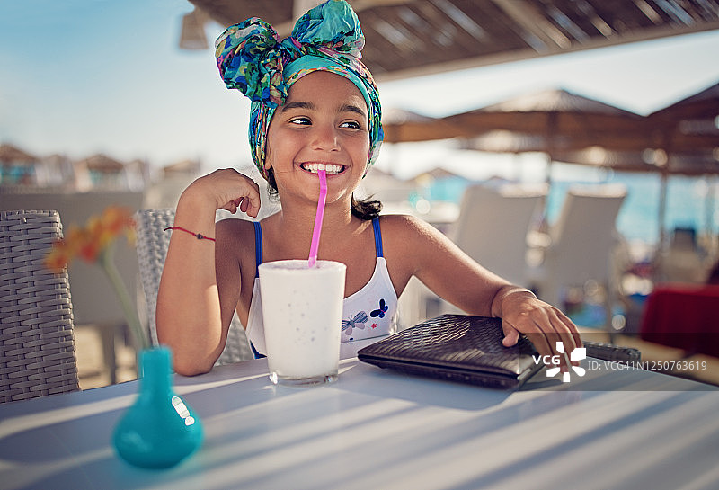 在海滩咖啡馆喝奶昔的小女孩图片素材