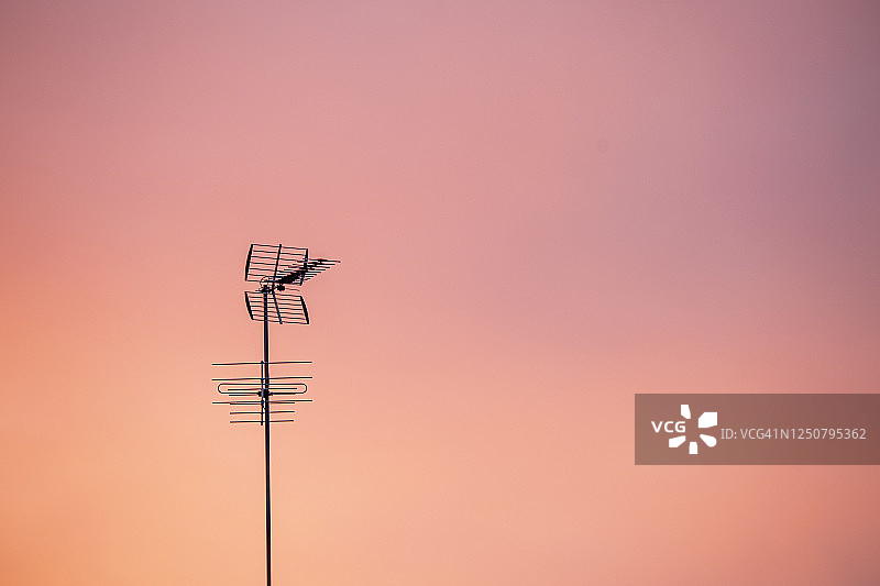 粉色日出下的电视天线电缆图片素材