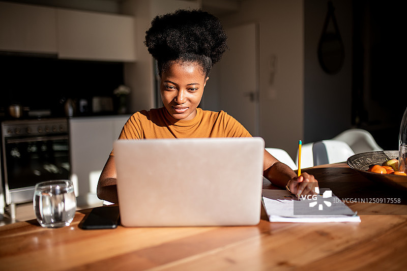 年轻女人对着电脑阅读并做笔记图片素材