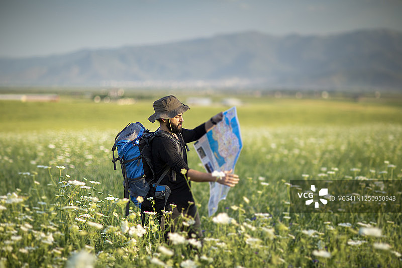 男人独自走在日落时的绿色草地上图片素材