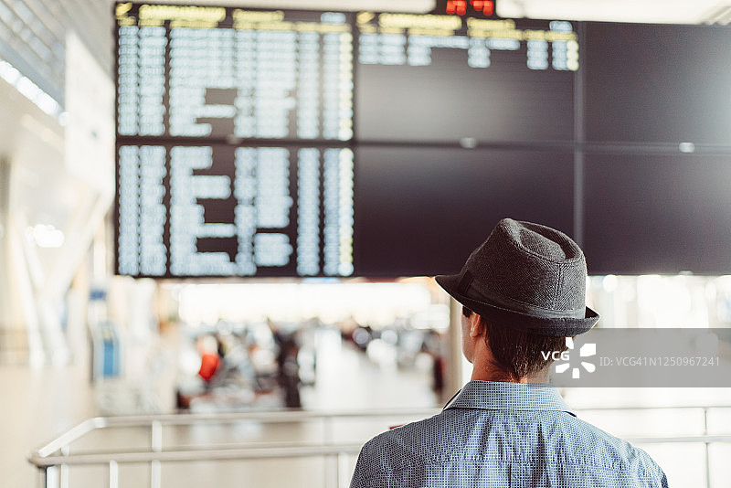 游客在机场查看到达和离开信息显示屏图片素材