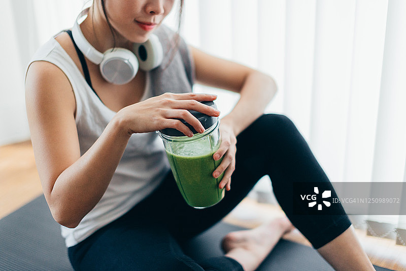 做瑜伽后喝绿色冰沙的年轻亚洲女性图片素材