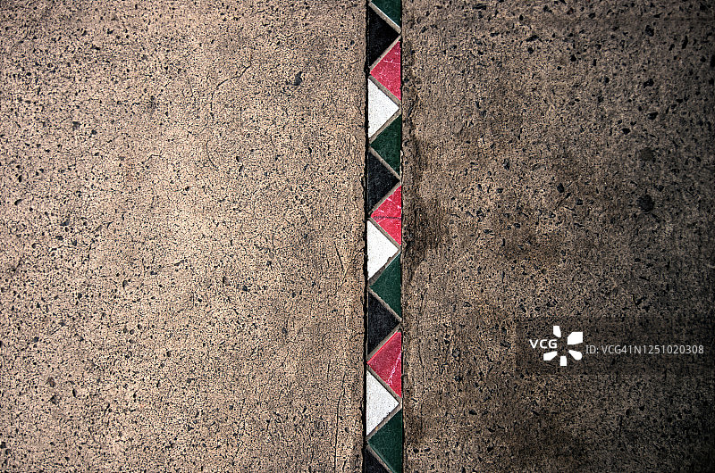 脏水泥人行道上的彩色三角形瓷砖图片素材