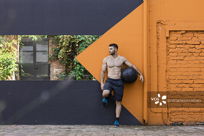 健身之后：健壮的男人赤膊拿着药球图片素材