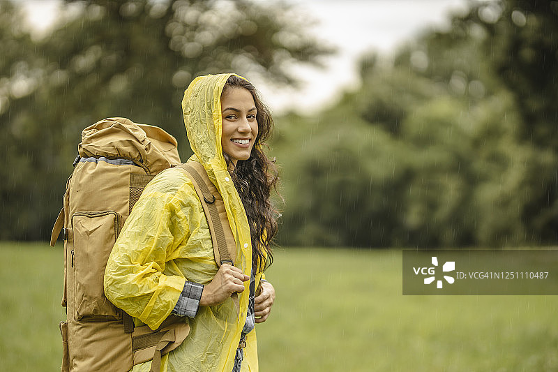 身穿防水夹克在雨中徒步的年轻女子图片素材