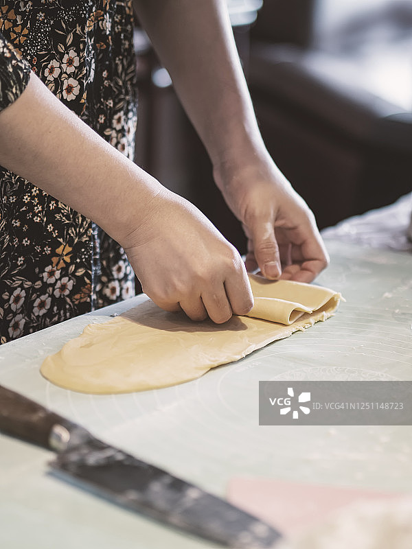 女人在餐桌上揉搓片状面团制作意大利面图片素材