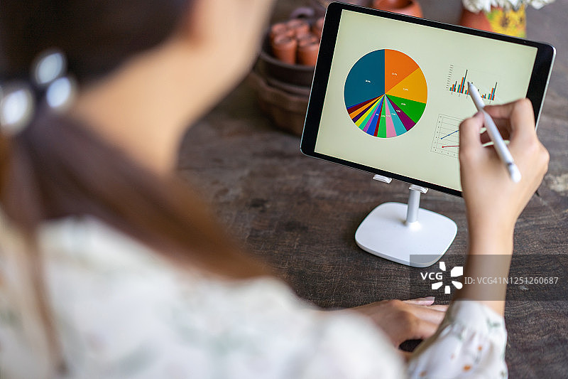 在后院木桌上使用数位板和触控笔的年轻亚洲女性图片素材