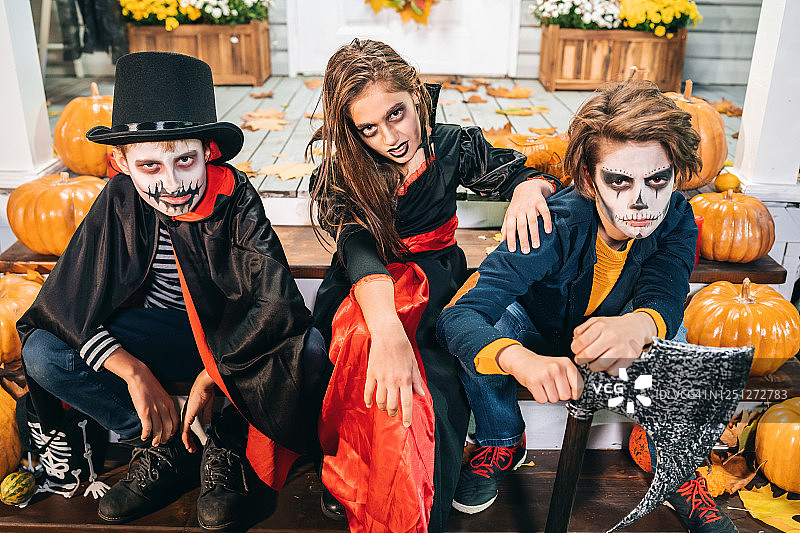 万圣节装扮的孩子们在房子前的楼梯上玩“不给糖就捣蛋”游戏图片素材