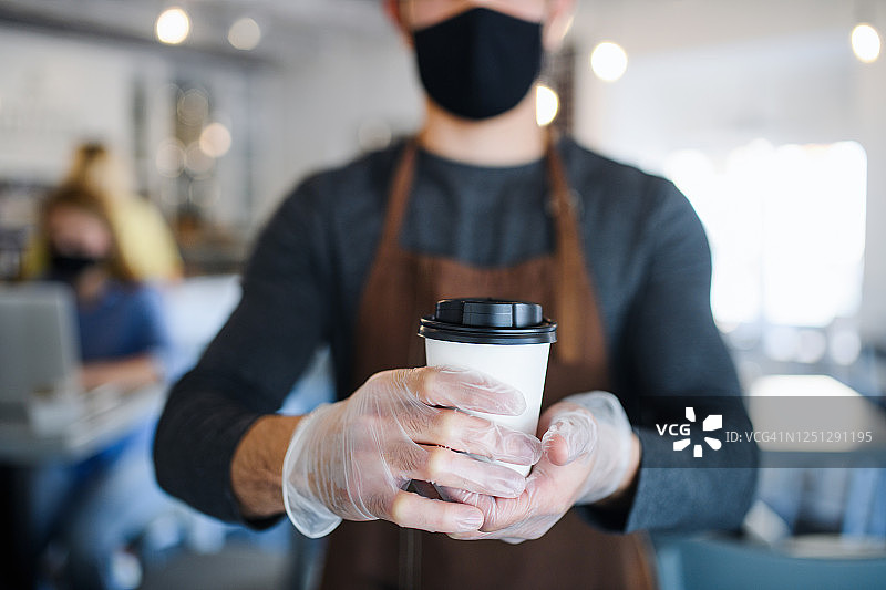 咖啡店里戴口罩和手套的年轻咖啡师正在制作咖啡图片素材