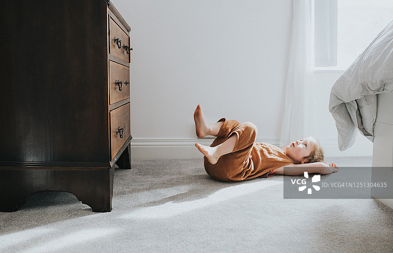 儿童躺在灰色厚绒地毯上，留下阴影图片素材