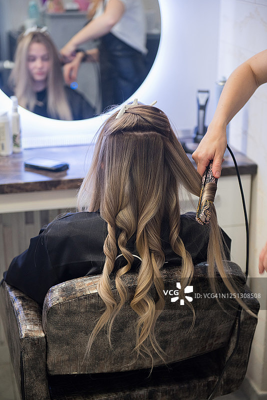 在美发沙龙做头发准备毕业典礼的年轻女孩图片素材