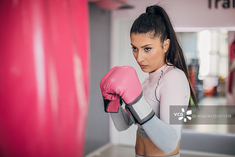 年轻女子用拳击袋训练图片素材