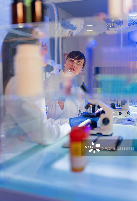 女性实验室团队使用显微镜研究病原体样本图片素材