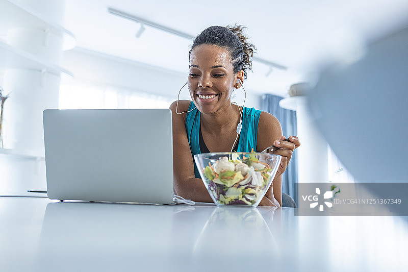 快乐的非洲裔美国健身女性在吃蔬菜沙拉图片素材