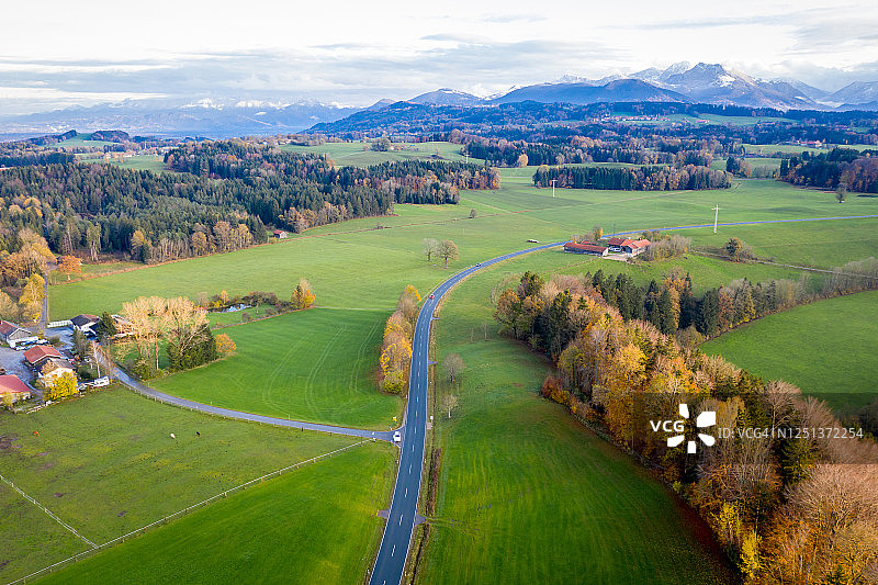 巴伐利亚米斯巴赫秋季：道路通向远方，阿尔卑斯山峰在天边航拍景观图片素材