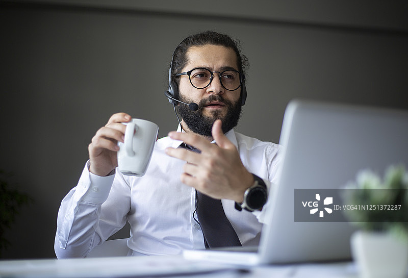 微笑的商务人士戴着耳机在笔记本电脑上进行视频会议图片素材