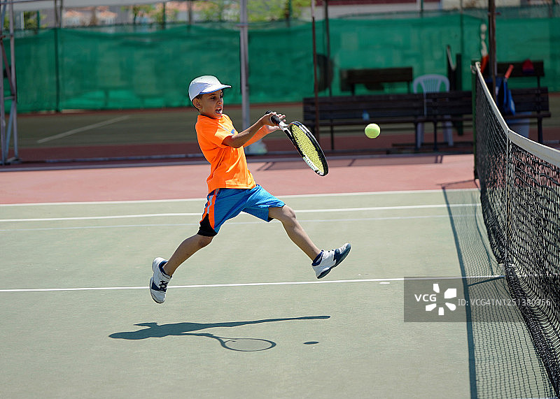 男孩在硬地球场上正手击球，打网球图片素材