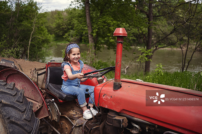 乡村女孩在田野驾驶拖拉机图片素材
