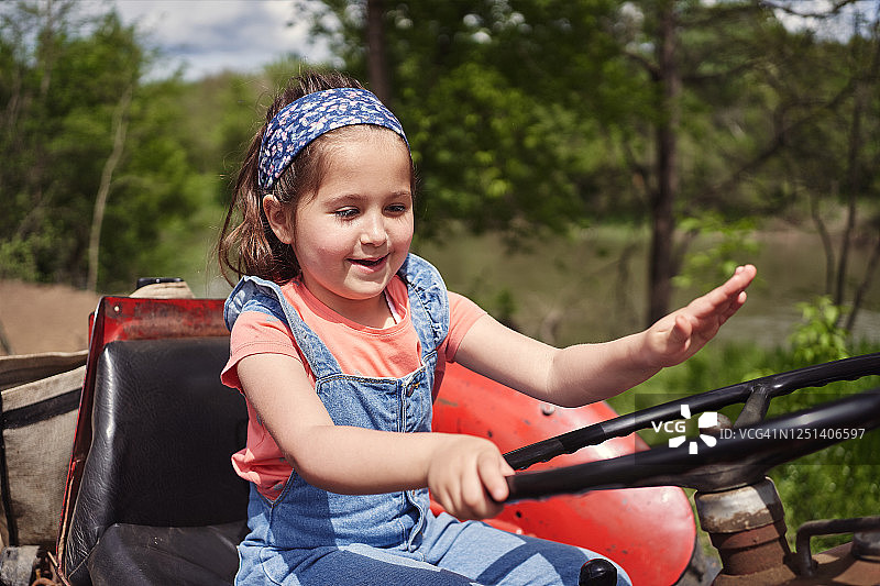 驾驶红色拖拉机的聪明小女孩图片素材