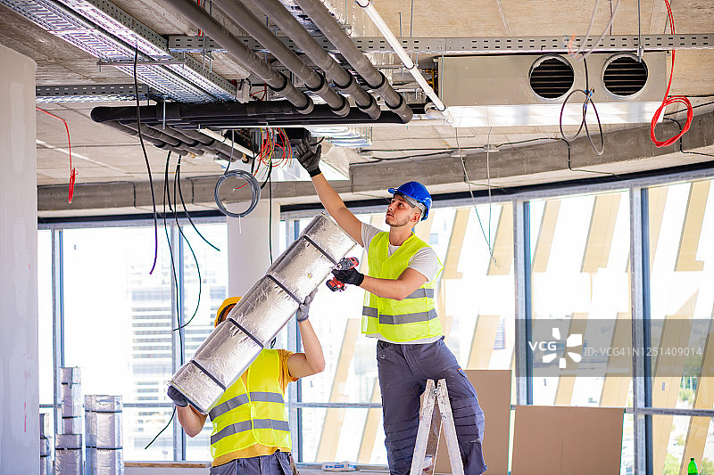 男人在室内安装通风系统图片素材