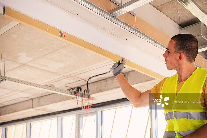 男人正在装修房屋并检查墙面水平图片素材