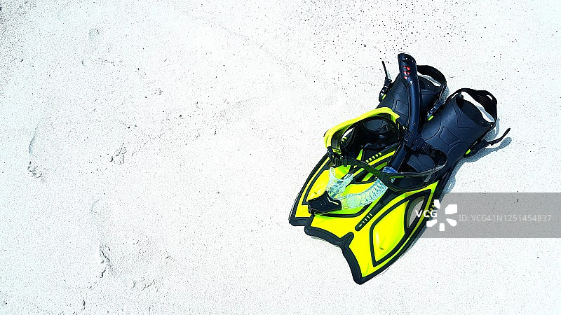 潜水概念：遗留在白色沙滩上的黄色潜水脚蹼图片素材