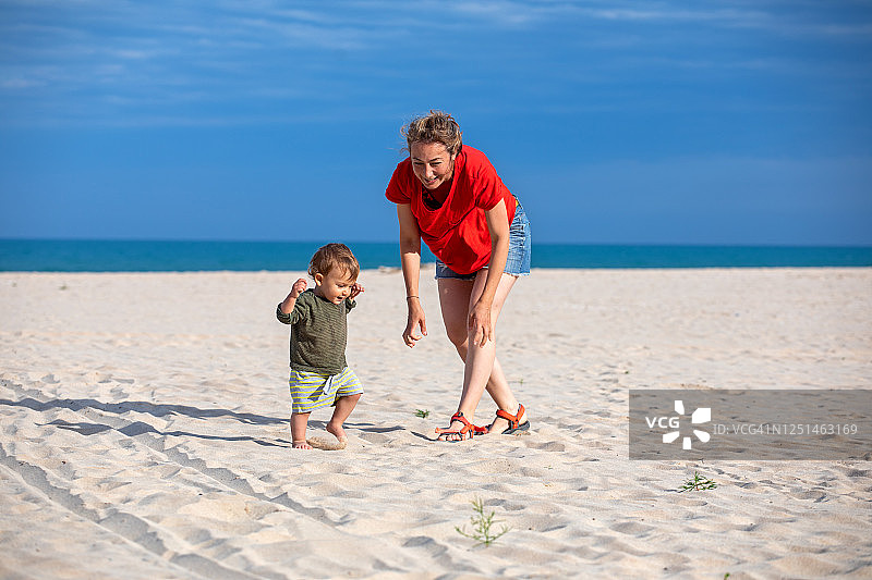 年轻母亲在沙滩上和幼儿玩耍图片素材