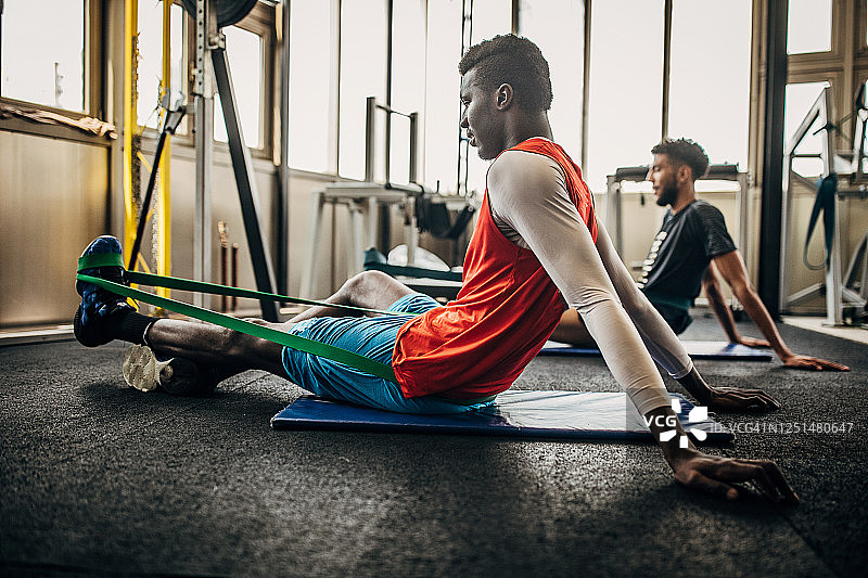 两个年轻男人在健身房一起伸展身体，是排球运动员图片素材