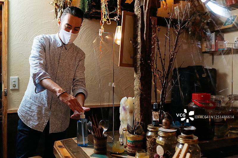 男人在小酒吧使用洗手液，采取疾病安全措施图片素材