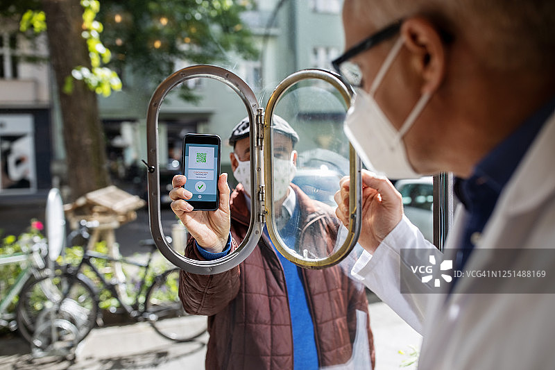 顾客向药剂师展示COVID-19应用程序后进入商店图片素材