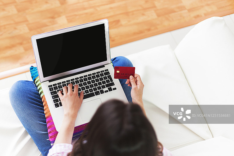 俯视角度：女人在家用笔记本电脑和借记卡进行网上购物图片素材